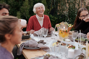 Grandmother laughing at an outdoor dining table with family